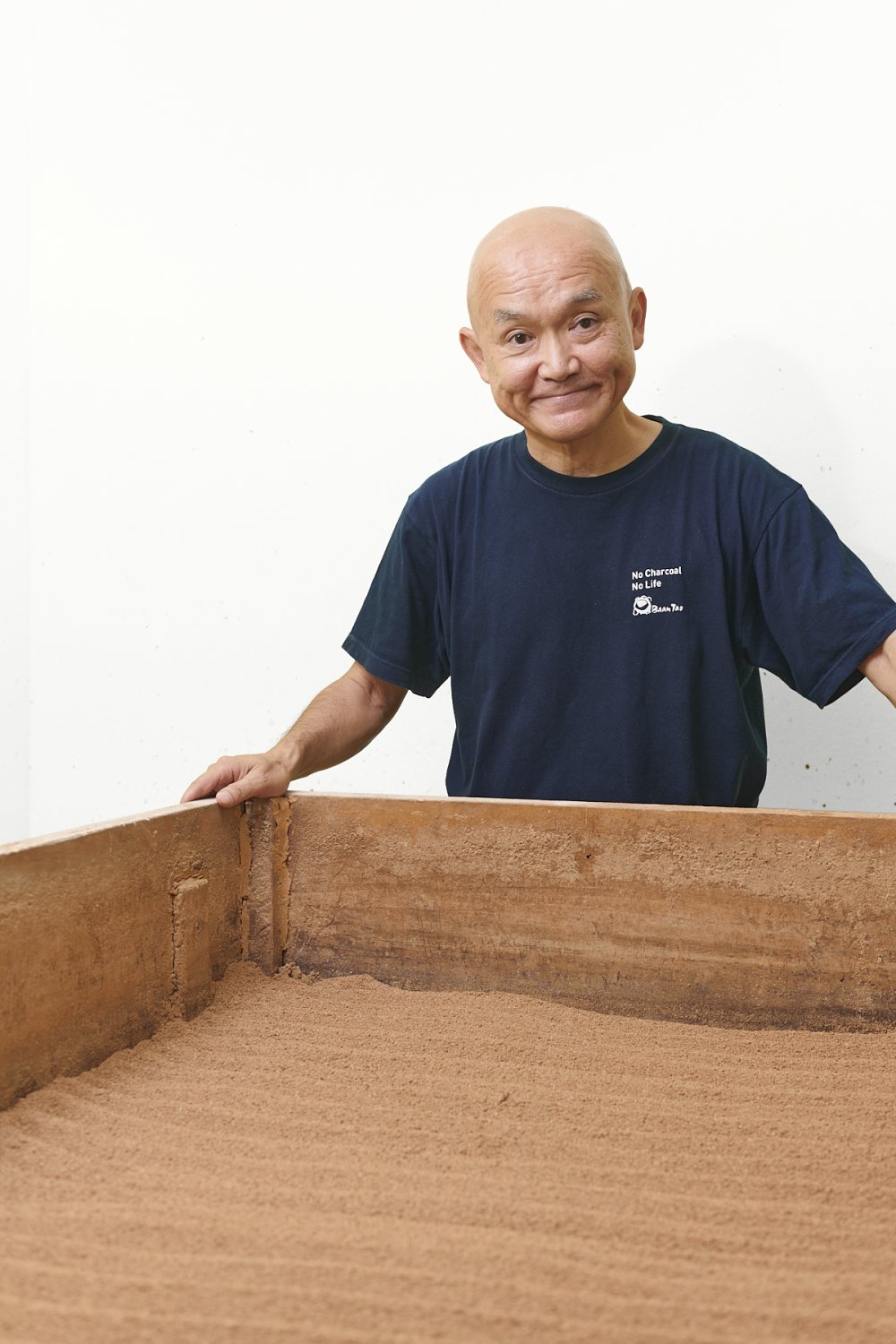 木箱に手を添えて微笑む代表の立ち姿